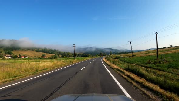 POV shot of driving a car on the road along the forest and mountains. Traveling in the summer by car alt