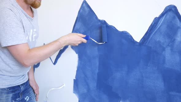 close-up man paints mountains on the wall in blue