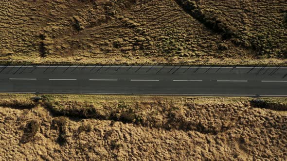 Aerial top down view of cars on a countryside road through an ample desolate