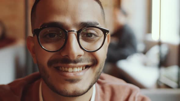 Young Joyous Middle Eastern Man Smiling at Camera in Cafe