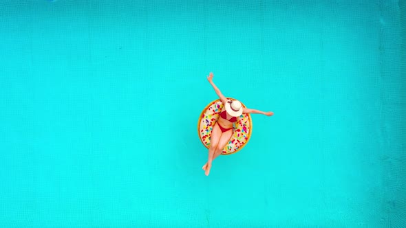 Aerial View of a Woman in Red Bikini Lying on a Donut in the Pool