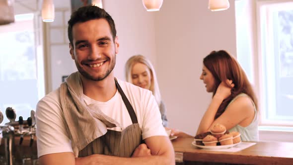 Portrait of smiling waiter standing with arms crossed