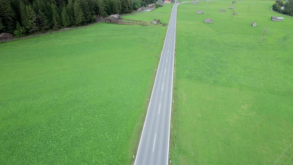 Empty Asphalt Road in Austria Between Green Fields in the Alps Aerial View