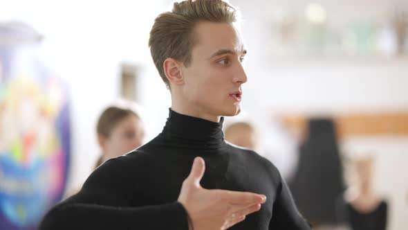 Side View of Confident Male Dance Teacher Explaining Dance To Children and Teens in Dancing School