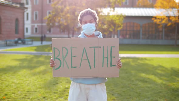 Portrait of African-american Woman Wearing Safety Mask Standing with Cardboard Sign Breathe Outdoors