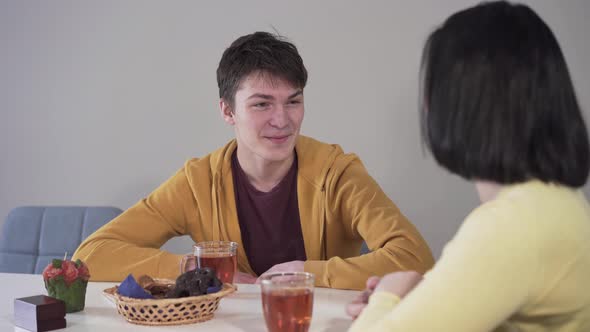 Portrait of Smiling Caucasian Brunette Boy Talking with Mother As Sitting at the Table with Tea