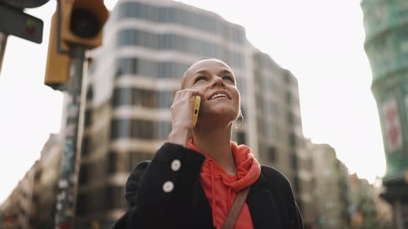 Cheerful bald woman talking by phone