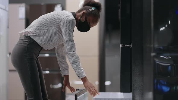 Black Woman is Viewing Freezer of Refrigerator in Home Appliance Store Viewing Exhibition Sample