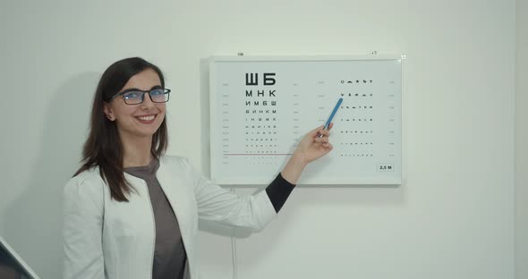 Ophthalmologist in a White Coat Near the Vision Board