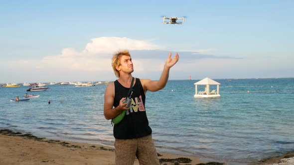 Young Caucasian Man Catch the Drone on the Beach