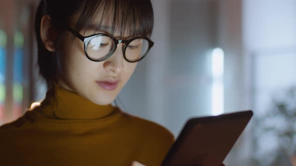 Asian Businesswoman Using Digital Tablet in Dark Office