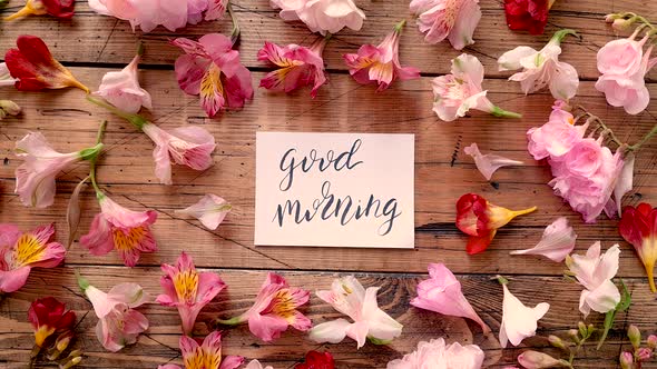 GOOD MORNING card near flowers on a wooden table top view