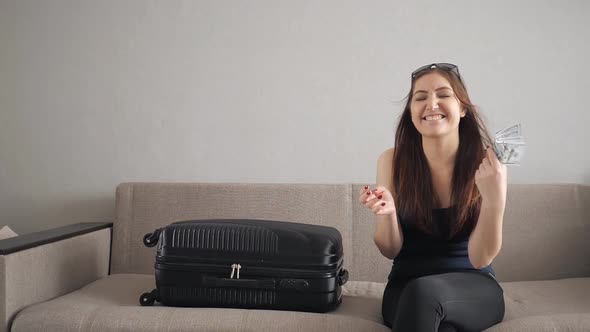 Slow Motion of Girl with Suitcase Sits on the Couch and Throws Dollars Up