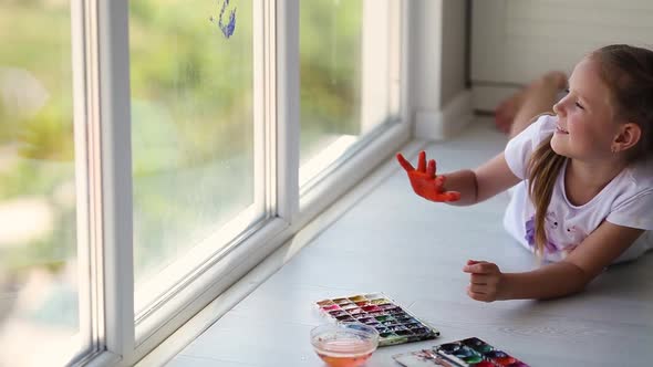 Children girl draw with palms on the window.