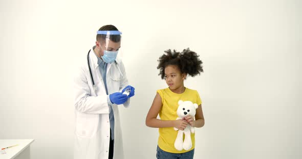 Male Pediatrician Giving a Vaccine Shot to a Black Kid