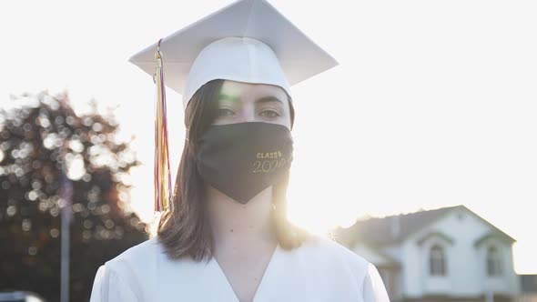 Young woman in cap and gown wearing face mask