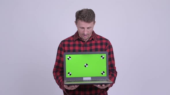 Happy Bearded Hipster Man Looking Surprised While Showing Laptop