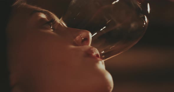 Young woman finises red wine from wineglass close up