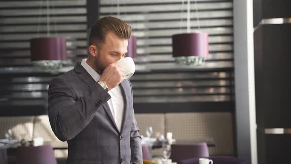 Handsome Young Man Drinking Cup of Coffee in Restaurant