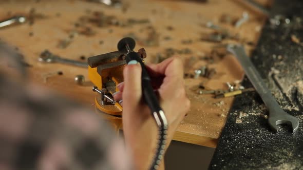 Woman using power working grinder machine, female hand grinds a metal nuts