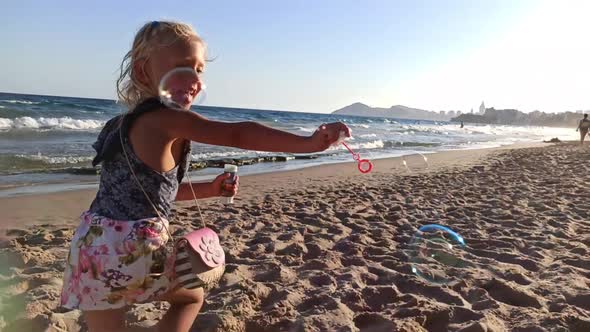 Child Blows Soap Bubbles on the Beach