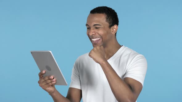 Young African Man Excited for Success While Using Tablet