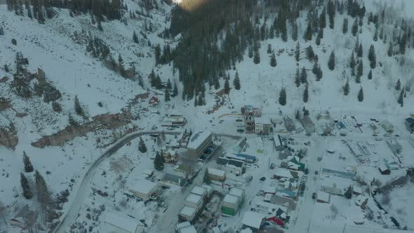Aerial Drone Shot Descending Towards Small Mountain Town in Snowy Valley