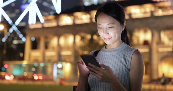 Woman using mobile phone in city at night 