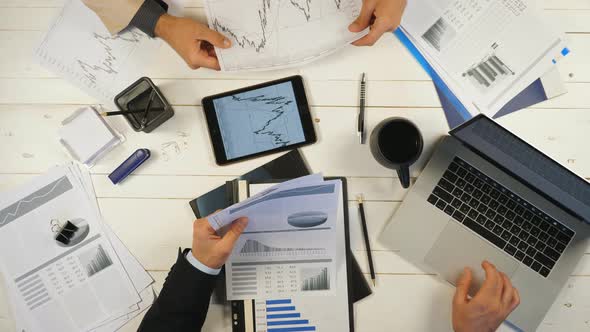 Top View Male Hands of Two Businessmen Looking and Examining Graphs with Financial Reports in Office