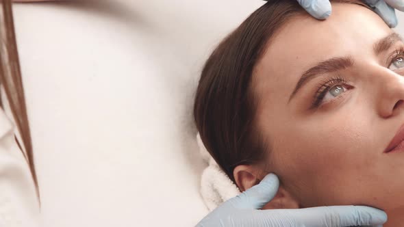 Close-up of Cosmetologist Arms Checking Female Face