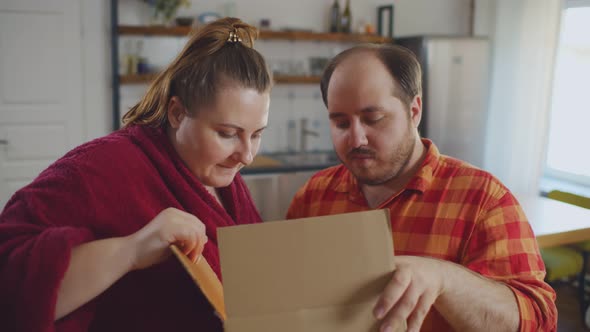 Excited Overweight Couple Unpack Internet Order Parcel at Home