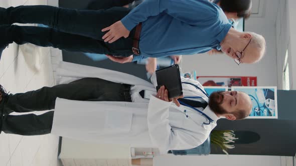 Vertical Video Doctor and Senior Patient Looking at Digital Tablet in Hospital Reception