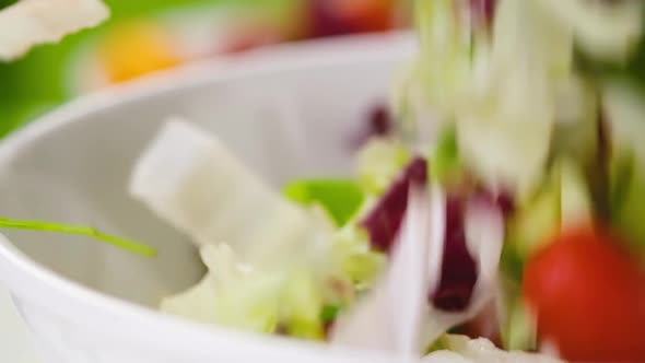 Fresh Salad Falling in Bowl on Green Background