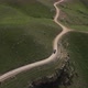 Top view on the driving car of the mountain road through the green field - VideoHive Item for Sale