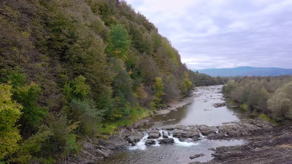 Mountain river with cold clear water. The river flows over the stones with little waterfall.