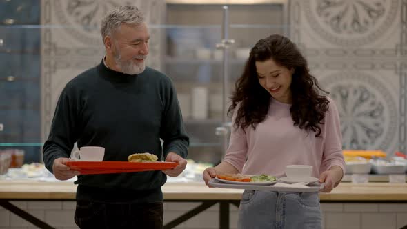 Cheerful Senior Father and Adult Daughter Walking with Trays and Talking in Selfservice Restaurant