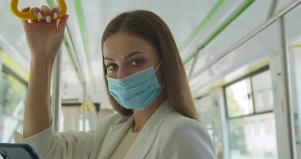 Close Up Portrait of Beautiful Woman in Medical Mask and Gloves Staying at Public Transport. Concept