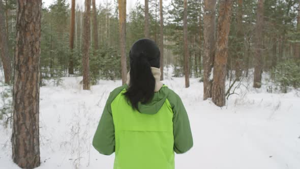 Rear View of Woman Jogging in Forest in Winter