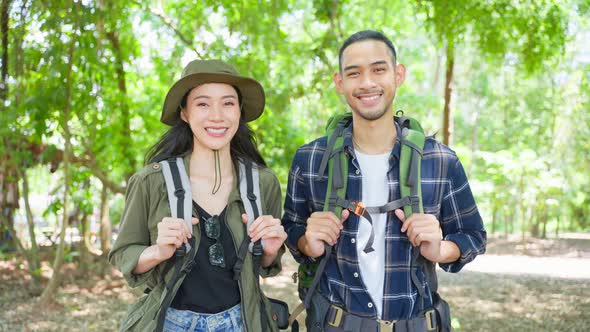 Portrait of Asian man and woman backpacker travel in forest together.