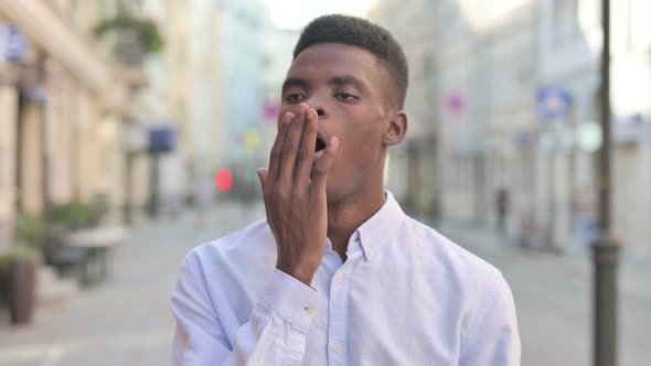 Sleepy African Man Yawning While Standing Outdoor