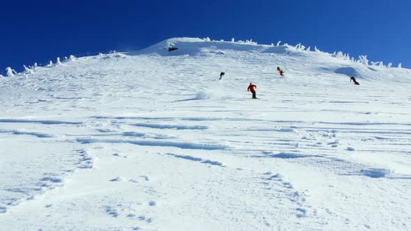 People snowboarding on snowy mountain