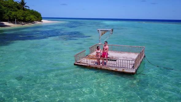 Family of two engaged on relaxing coast beach adventure by blue green ocean with white sandy backgro