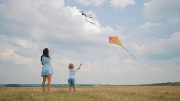 Happy Family Mom and Son Playing with Flying Kite on Meadow in Beautiful Sunny Day Blue Sky