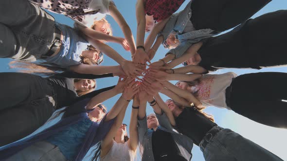 Cheerful Girlfriends Make Their Hands Together on a Sunny Day