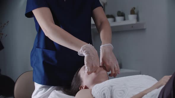 Blonde Woman Massagist Doing a Face Massage Using Her Fingers on Her Female Client