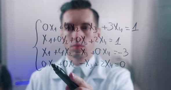 Male Scientist Thinks Over the Solution of the Equation Drawn on a Glass Board in a Laboratory