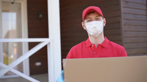 Portrait of deliverer wearing safety mask holding a box. Service in quarantine.