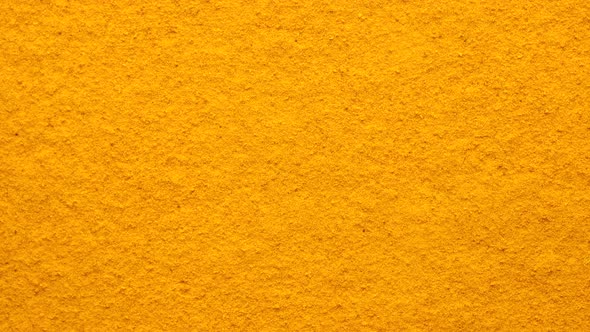 Turmeric powder top view rotating. Condiment or dietary supplement