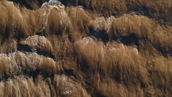 A fast flowing muddy river creating waves and patterns from the fast flowing current