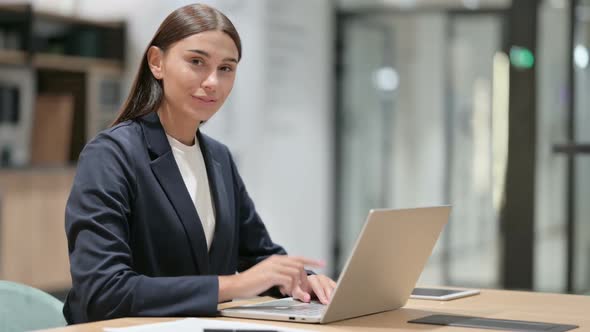 Businesswoman with Laptop Pointing at the Camera